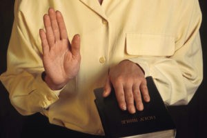 expert witness with hand on bible