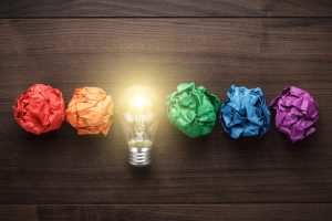great idea concept with crumpled colorful paper and light bulb on wooden table