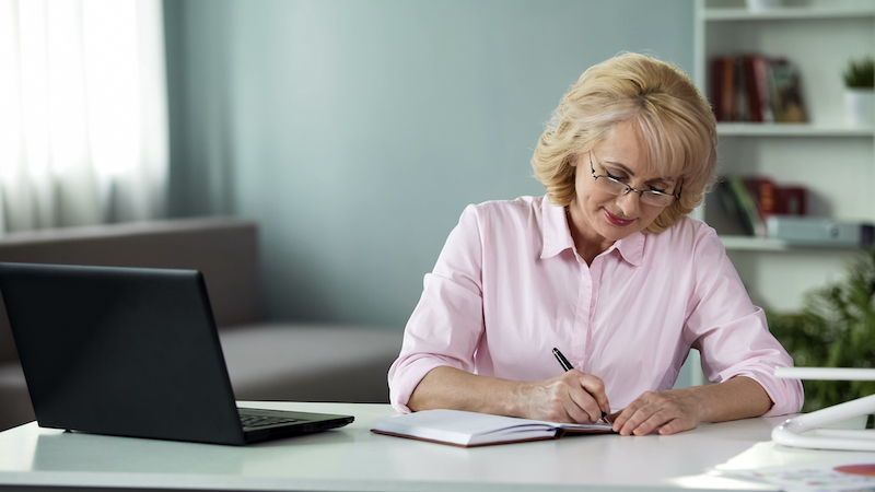 Business woman writing down to notebook plan for near future